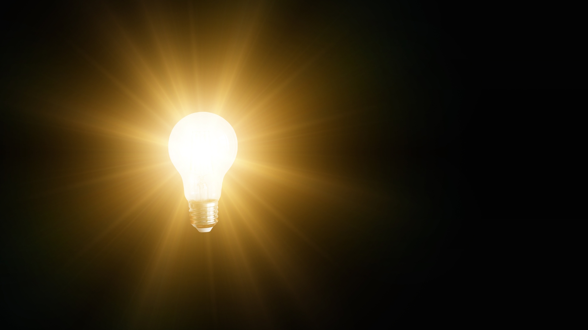 Bombilla encendida emitiendo luz sobre fondo negro, símbolo de idea brillante e innovación